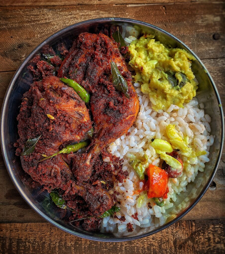 Delicious spicy chicken with rice and vegetables in a stainless steel bowl.
