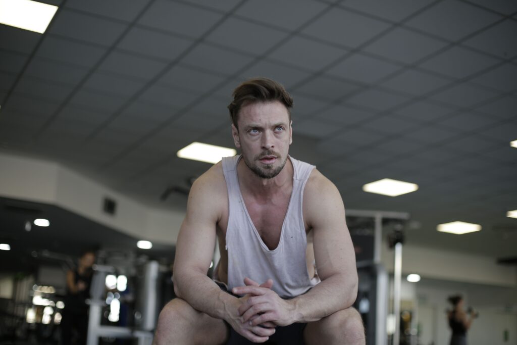 A man pauses to rest after a demanding exercise session at the gym, showcasing fitness and determination.